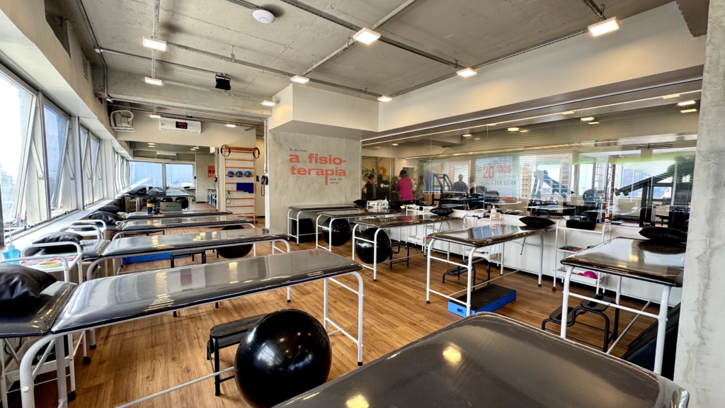Sala de fisioterapia da B-Active com macas e equipamentos para exercícios terapêuticos.